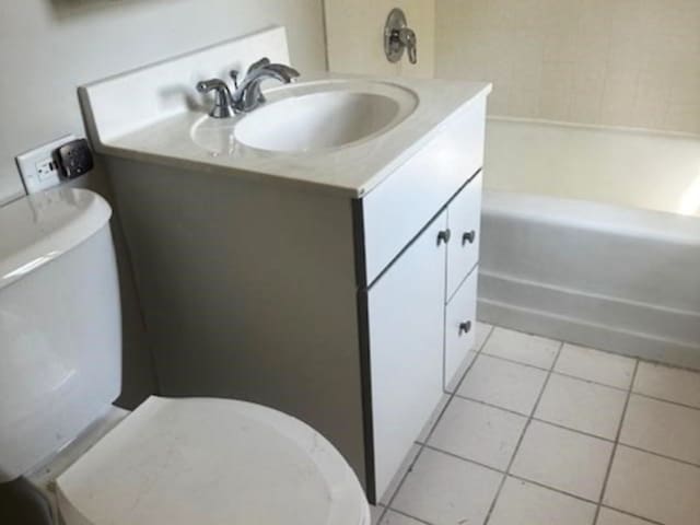 bathroom with tile patterned flooring, toilet, vanity, and a bathing tub