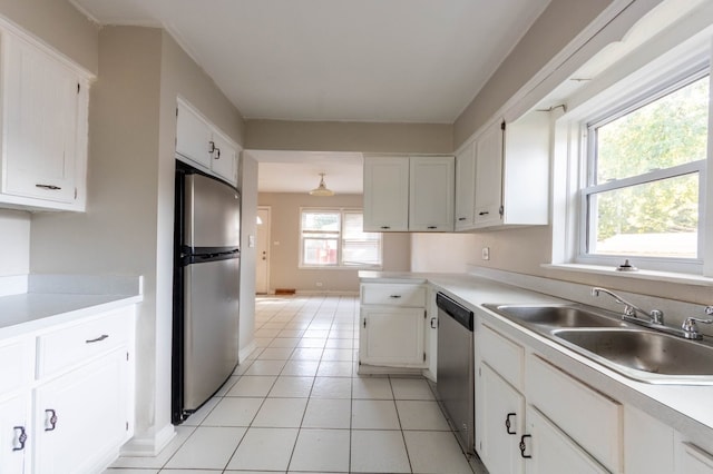 kitchen with light tile patterned floors, appliances with stainless steel finishes, sink, and white cabinetry