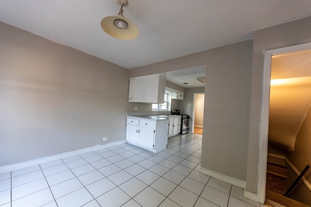 kitchen with light tile patterned flooring, stainless steel stove, and white cabinets