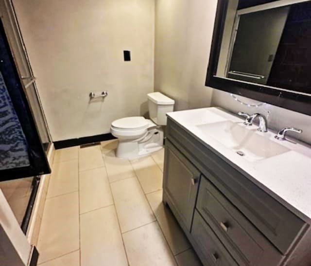 bathroom with a shower with door, tile patterned floors, vanity, and toilet