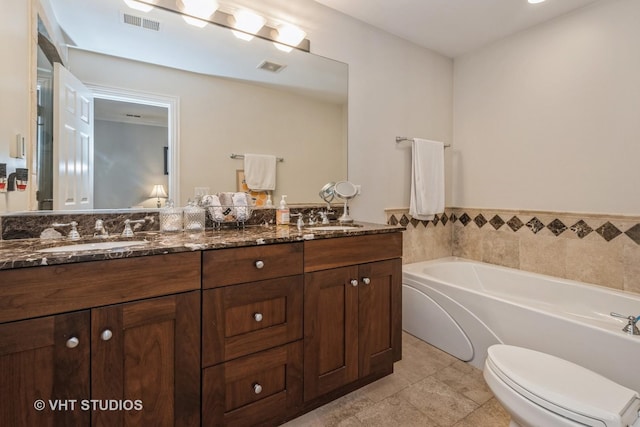 bathroom with a washtub, toilet, vanity, and tile patterned flooring