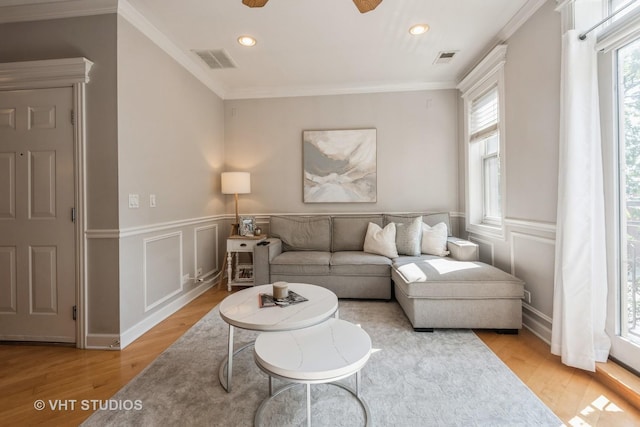 living room featuring ceiling fan, ornamental molding, and light hardwood / wood-style flooring