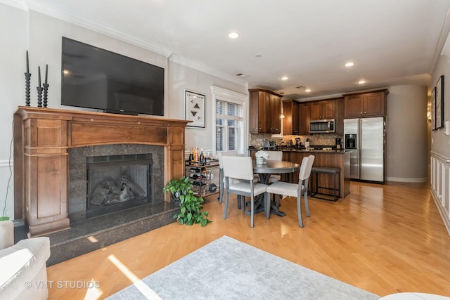 living room featuring light wood-type flooring, a high end fireplace, and crown molding