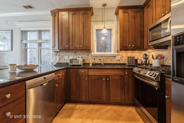 kitchen featuring stainless steel appliances, pendant lighting, tasteful backsplash, and sink