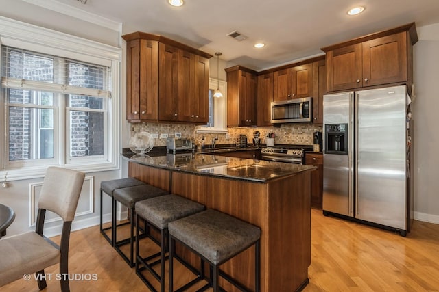 kitchen with dark stone counters, a kitchen breakfast bar, stainless steel appliances, and pendant lighting