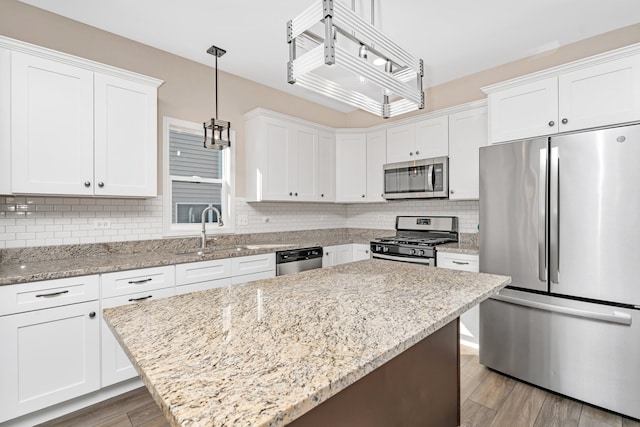 kitchen featuring pendant lighting, appliances with stainless steel finishes, sink, and white cabinetry