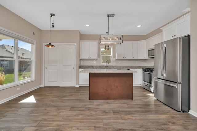 kitchen featuring stainless steel appliances, pendant lighting, a center island, and a wealth of natural light