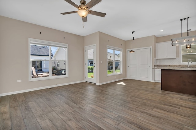 unfurnished living room with wood-type flooring, sink, and ceiling fan