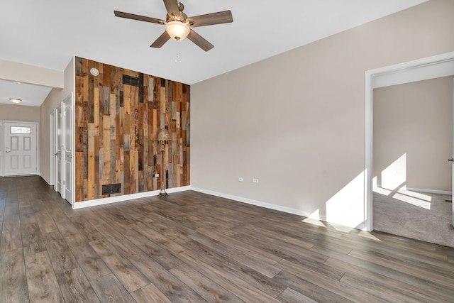 spare room featuring ceiling fan, wooden walls, dark hardwood / wood-style floors, and vaulted ceiling