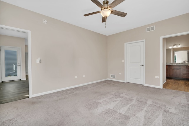 unfurnished bedroom with ceiling fan, light colored carpet, and ensuite bath