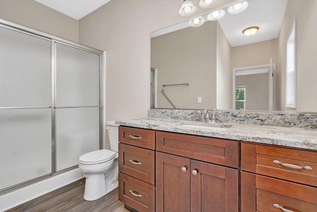 bathroom featuring wood-type flooring, vanity, toilet, and an enclosed shower