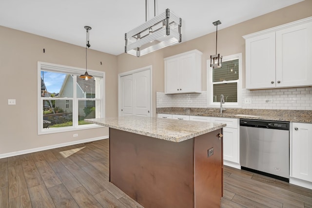 kitchen featuring light stone counters, white cabinets, pendant lighting, stainless steel dishwasher, and dark wood-type flooring