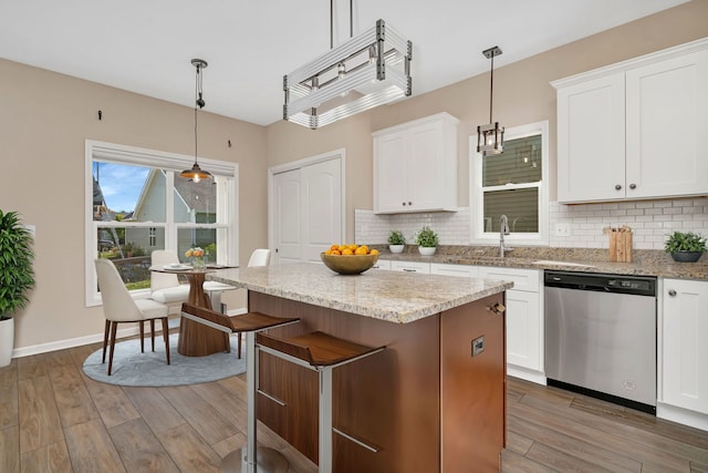 kitchen with pendant lighting, wood-type flooring, tasteful backsplash, dishwasher, and white cabinets