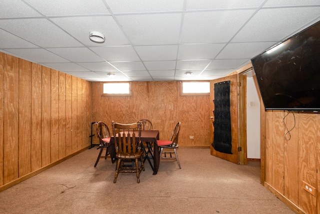 dining room with wood walls, a drop ceiling, a wealth of natural light, and light carpet