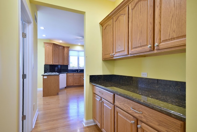 kitchen featuring dishwasher, dark stone counters, light hardwood / wood-style floors, and ceiling fan