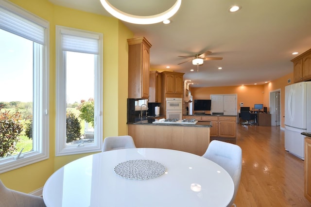 kitchen featuring ceiling fan, sink, kitchen peninsula, white appliances, and light hardwood / wood-style flooring