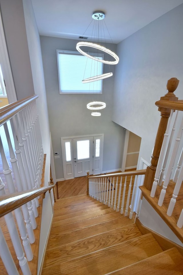 staircase featuring hardwood / wood-style flooring and a notable chandelier