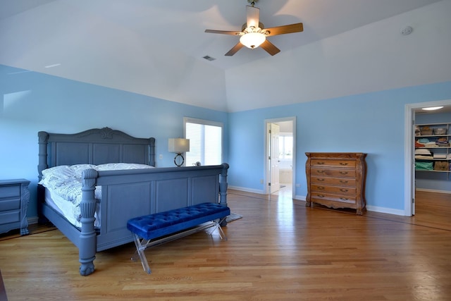 bedroom featuring a spacious closet, connected bathroom, hardwood / wood-style flooring, and ceiling fan