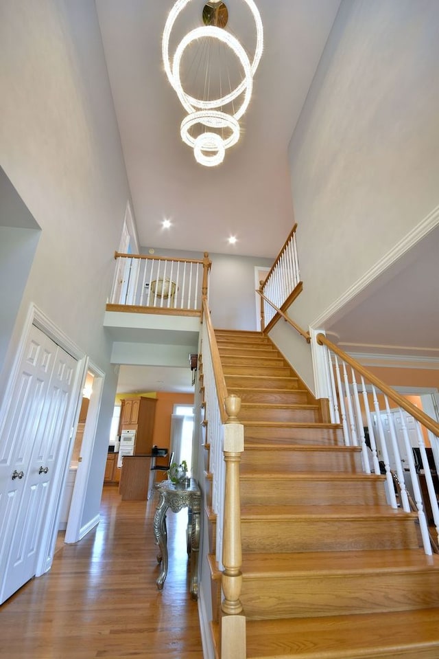 staircase with a high ceiling, a notable chandelier, and hardwood / wood-style floors