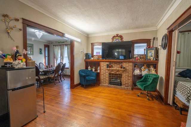 living room featuring ornamental molding, a brick fireplace, hardwood / wood-style floors, and a textured ceiling