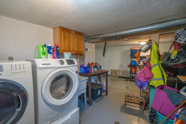 clothes washing area featuring a textured ceiling, washer and clothes dryer, and cabinets