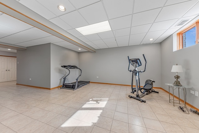 exercise area with a paneled ceiling and light tile patterned floors