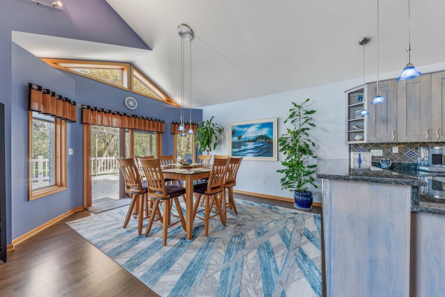 dining area with dark wood-type flooring and vaulted ceiling