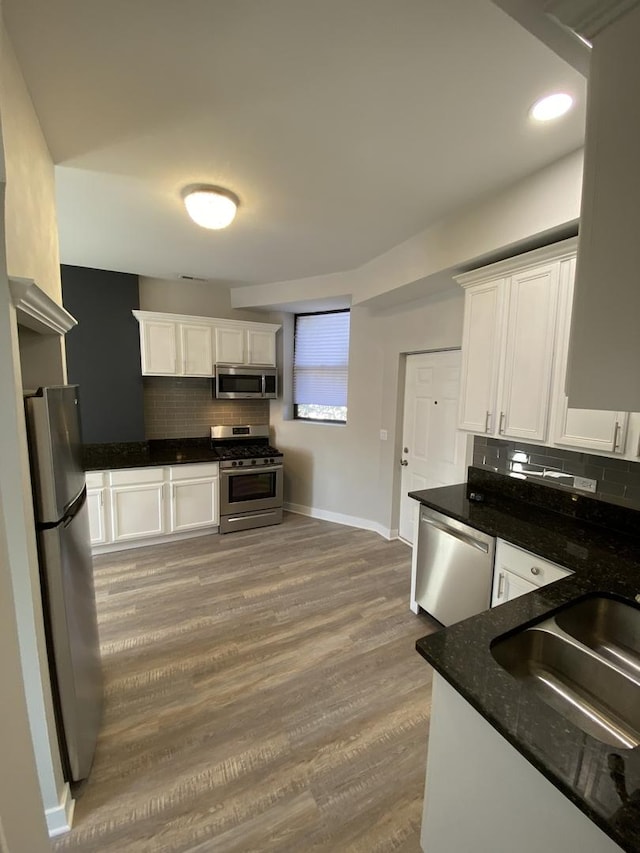 kitchen featuring backsplash, sink, hardwood / wood-style flooring, appliances with stainless steel finishes, and white cabinetry