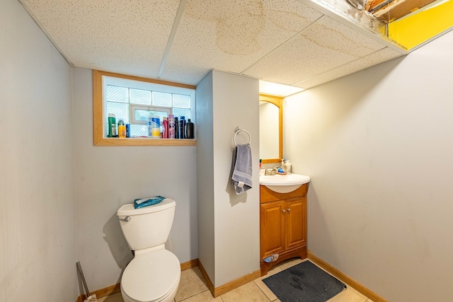 bathroom with a paneled ceiling, tile patterned flooring, vanity, and toilet