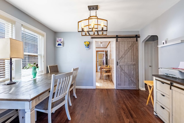 dining space with dark hardwood / wood-style floors, a barn door, and a chandelier