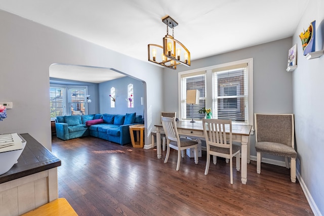 dining area with dark hardwood / wood-style floors, an inviting chandelier, and a healthy amount of sunlight