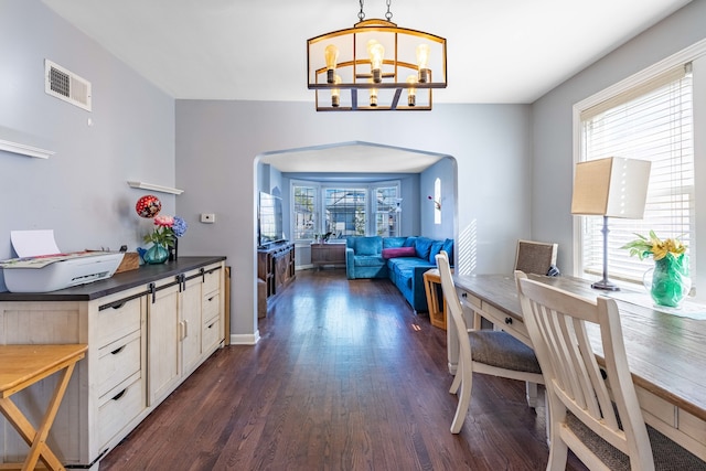 home office with a wealth of natural light, a chandelier, and dark hardwood / wood-style floors