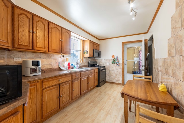 kitchen featuring ornamental molding, black appliances, sink, and light hardwood / wood-style flooring