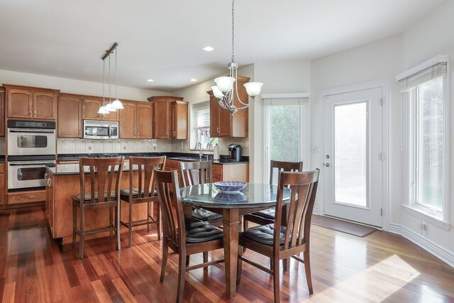 dining area with an inviting chandelier, dark hardwood / wood-style floors, and a healthy amount of sunlight