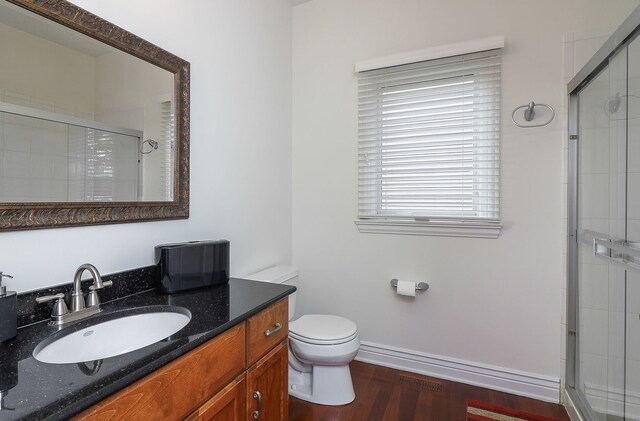 bathroom with vanity, hardwood / wood-style floors, toilet, and an enclosed shower