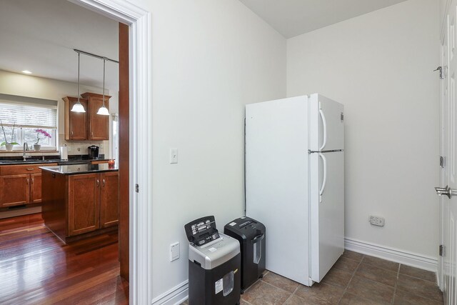 kitchen featuring dark wood-type flooring, sink, kitchen peninsula, hanging light fixtures, and white fridge