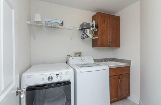 washroom with independent washer and dryer, cabinets, sink, and light tile patterned floors