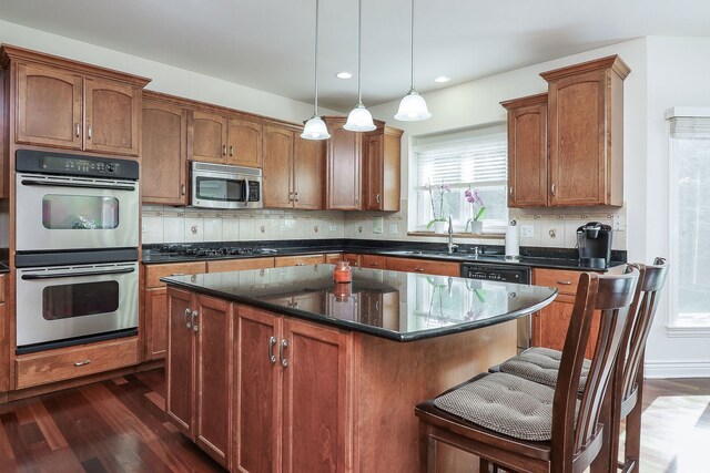 kitchen with tasteful backsplash, a kitchen island, dark wood-type flooring, sink, and appliances with stainless steel finishes