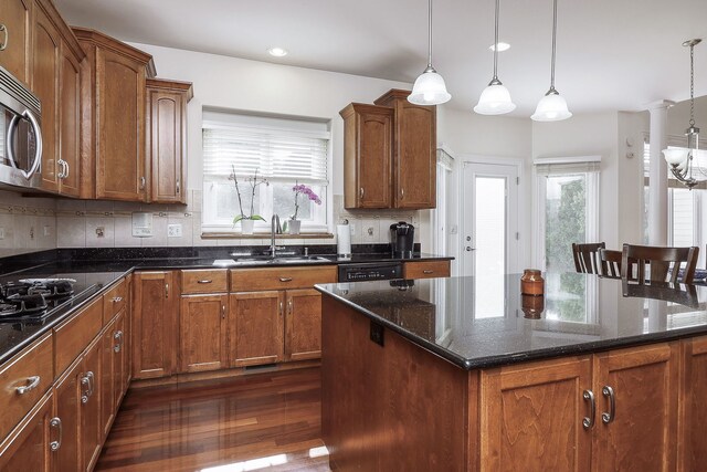 kitchen featuring a center island, decorative light fixtures, sink, and dark hardwood / wood-style floors