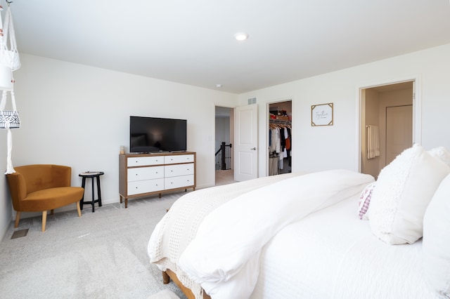 bedroom featuring a closet, a walk in closet, and light carpet