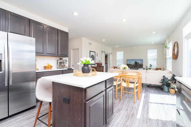 kitchen featuring light hardwood / wood-style flooring, dark brown cabinets, a center island, and stainless steel refrigerator with ice dispenser