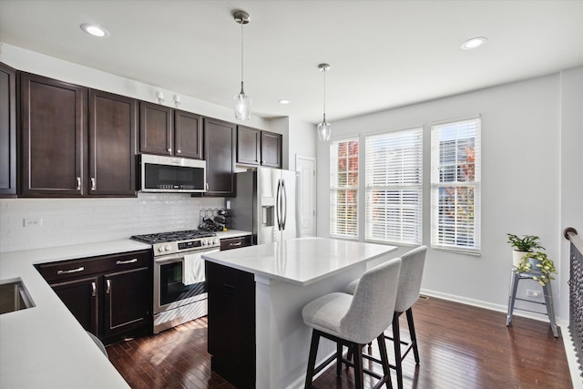 kitchen with decorative light fixtures, stainless steel appliances, dark hardwood / wood-style floors, and tasteful backsplash