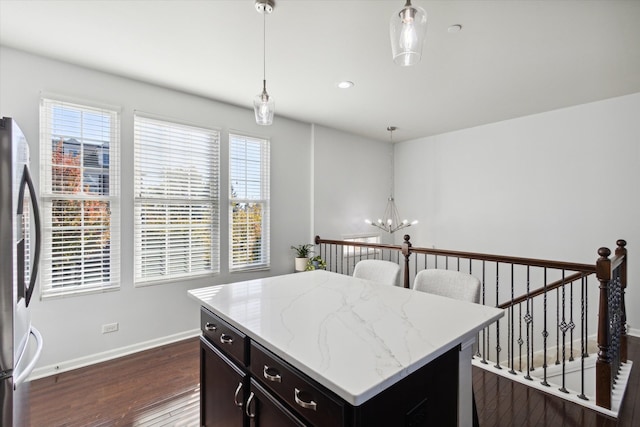 kitchen with a healthy amount of sunlight, hanging light fixtures, dark hardwood / wood-style flooring, and stainless steel fridge