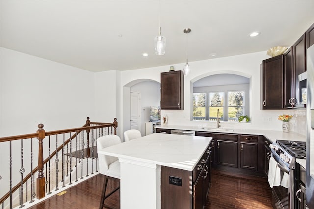 kitchen featuring sink, a center island, stainless steel appliances, a breakfast bar area, and dark hardwood / wood-style floors