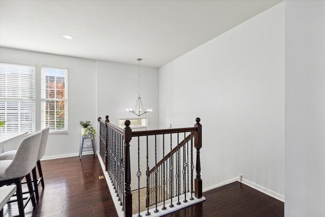 hall with dark hardwood / wood-style floors and an inviting chandelier