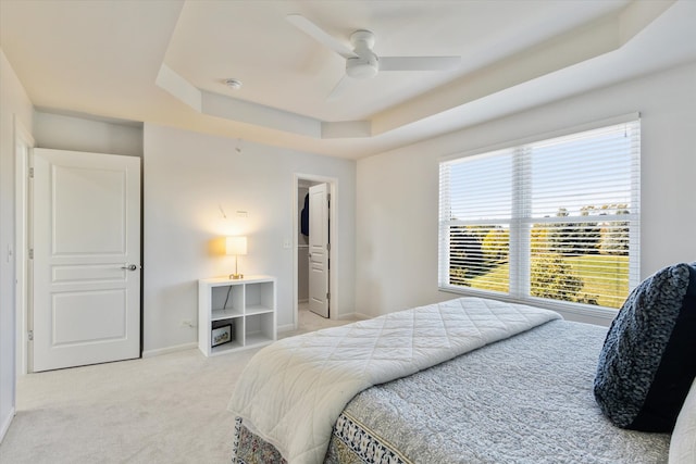 carpeted bedroom with a raised ceiling and ceiling fan