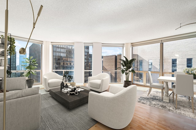 living room with hardwood / wood-style flooring, floor to ceiling windows, and a textured ceiling