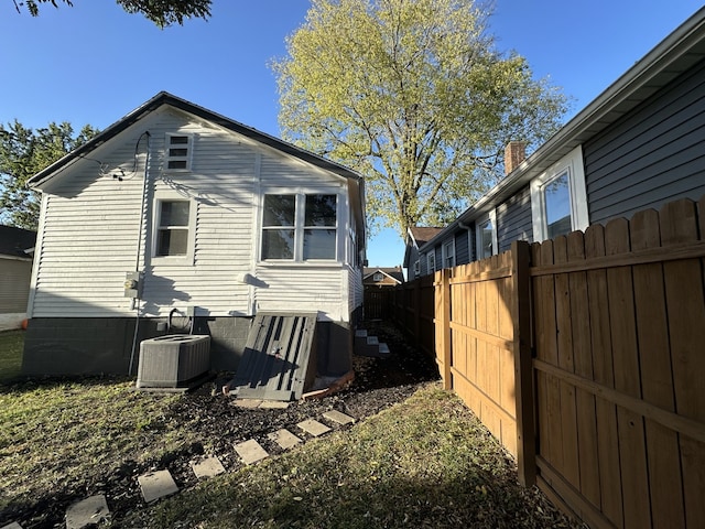 rear view of property with cooling unit, fence, and a chimney