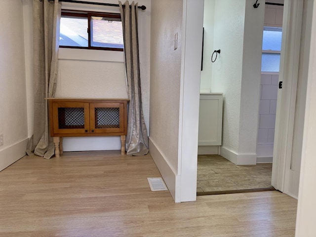 interior space featuring a textured wall, visible vents, a healthy amount of sunlight, and wood finished floors