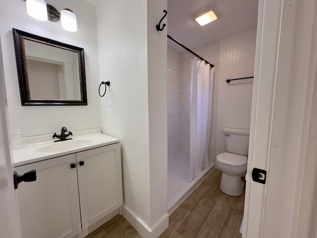 bathroom featuring toilet, wood finished floors, a textured wall, and vanity